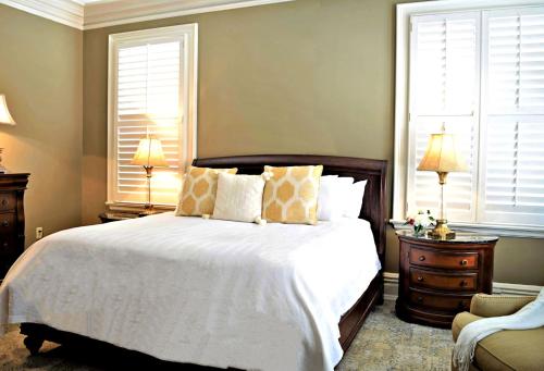 a bedroom with a large white bed and two windows at JH Adams Inn, Trademark Collection by Wyndham in High Point