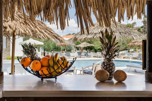 Anemousa Studios في Otziás: وعاء من الفواكه على طاولة بجوار حمام سباحة