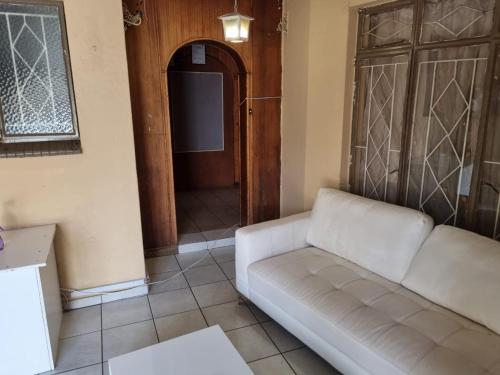 a living room with a white couch and a door at Miami guest house in Vereeniging