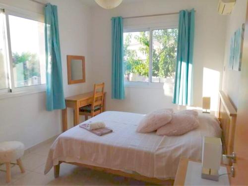 a bedroom with a bed with pillows and blue curtains at Peyia Resort Apartment in Peyia