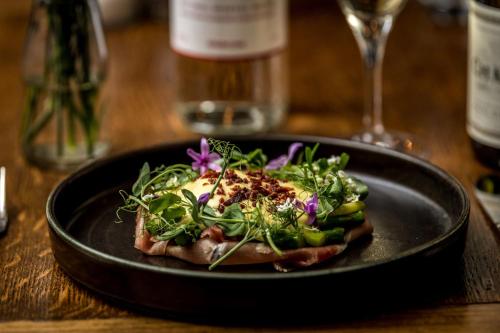 a black plate with a salad on a table at The Queen's Arms in Hungerford