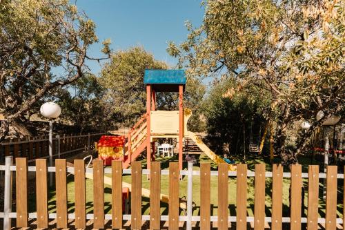 a playground in a park with a wooden fence at Anemousa Studios in Otzias