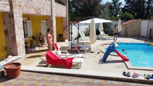 a group of people standing around a swimming pool at Apartments Villa Mimi in Višnjan