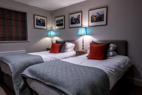 two beds in a room with two lamps and pictures on the wall at The Queen's Arms in Hungerford