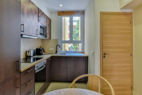 Elle comprend une petite cuisine avec des placards en bois et une fenêtre. dans l'établissement Cozy apartment Juan-Les-Pins 200m Beach, à Antibes