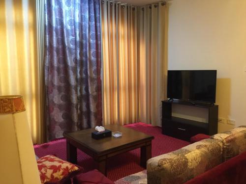 a living room with a couch and a flat screen tv at Regency Hotel Hebron in Hebron