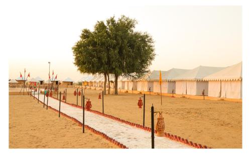 uma fileira de bandeiras e uma árvore numa praia em Shiv Tara Desert Camp em Sām