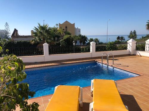 een zwembad met twee gele stoelen ernaast bij Casa Rosi, vistas al mar, piscina privada y A/A in Nerja