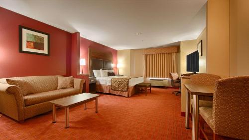 a hotel room with a bed and a couch and chairs at Best Western Plus Tulsa Woodland Hills Hotel and Suites in Tulsa
