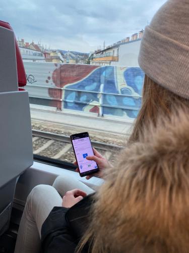 a woman sitting on a train while looking at a tablet at BeFree Hostel - Self-Service in Vienna