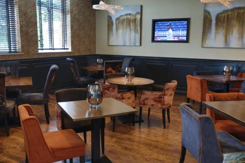 a dining room table with chairs and a television at The Eccleston Hotel; BW Signature Collection in Saint Helens