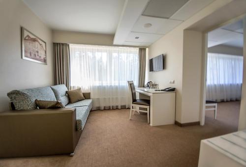 a living room with a couch and a desk in a room at Noorus SPA Hotel in Narva-Jõesuu