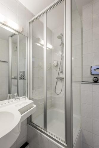 a white bathroom with a shower and a sink at Hotel Belmont Classic in Bonn