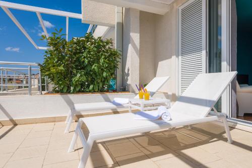 two white chairs sitting on a patio on a balcony at Apartments Villa Azzurra Bol in Bol