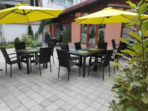 a patio with tables and chairs and yellow umbrellas at Hotel House K21 in Sofia