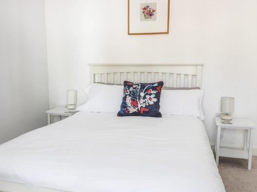a white bed with a blue pillow on it at Castlebrae in Jedburgh
