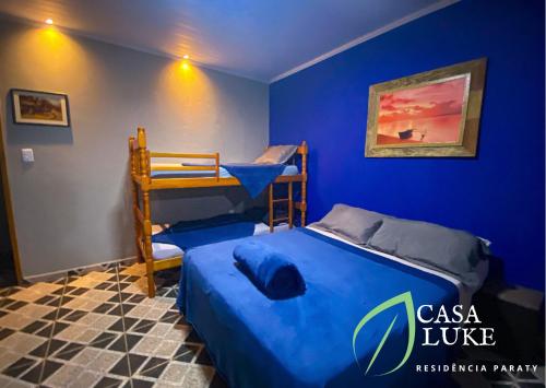 a bedroom with a blue wall with a bed and bunk beds at Casa Luke Paraty - Praia e cachoeira in Paraty