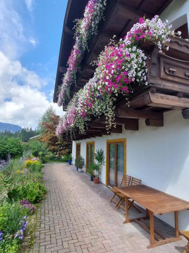 um edifício com flores penduradas no toldo e um banco de madeira em Stony Sea Apartments em Saalfelden am Steinernen Meer