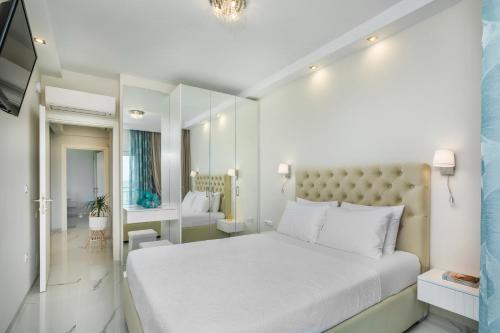 a white bedroom with a large bed and a bathroom at Beach Front Casa Elena in Hanioti