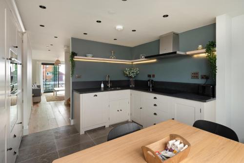 a kitchen with white cabinets and a wooden table at Home with sea views next to the beach! in Kent