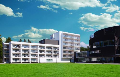 a white building with a grass field in front of it at Noorus SPA Hotel in Narva-Jõesuu