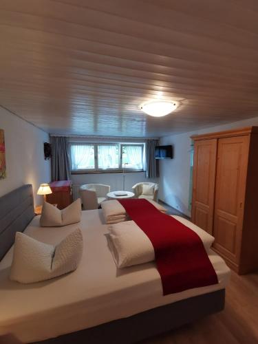 a bedroom with a large white bed with a red blanket at Landhaus Thaler in Mittelberg