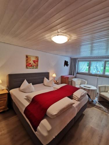 a bedroom with a large bed with a red blanket at Landhaus Thaler in Mittelberg