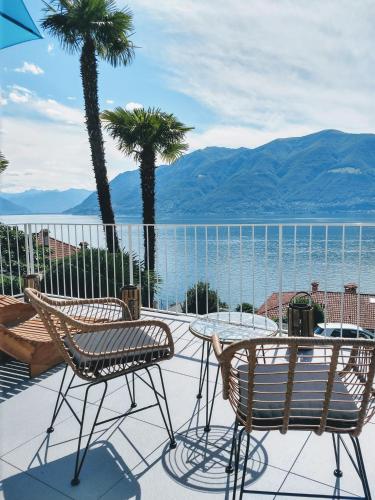 a patio with two chairs and a table and palm trees at Garden Hotel Primavera in Brissago