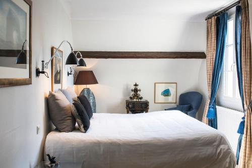 a bedroom with a white bed and a blue chair at La Mare aux Oiseaux, The Originals Collection in Saint-Joachim