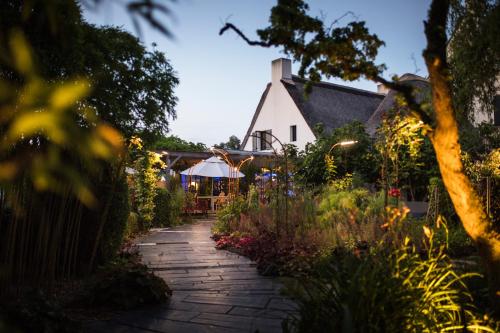 a garden path leading to a house with lights at La Mare aux Oiseaux, The Originals Collection (Relais du Silence) in Saint-Joachim