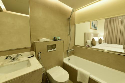 a bathroom with a sink and a toilet and a mirror at Saray Deluxe Hotel Apartments in Abu Dhabi