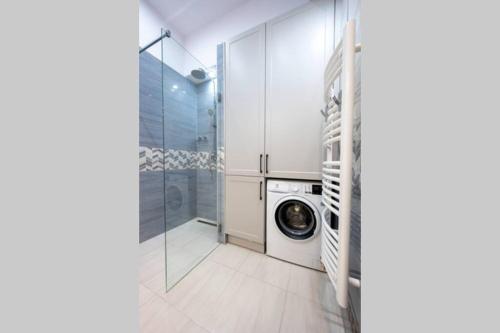 a laundry room with a washing machine and a glass door at Luxus a város felett in Szombathely
