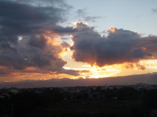 a sunset with clouds in the sky over a city at Anthurium Inn in Mactan