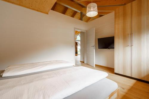 a bedroom with a white bed and a flat screen tv at Ferienwohnung Schreierhof Bio Bauernhof in Feldkirchen in Kärnten