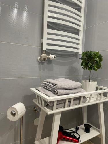 La salle de bains est pourvue d'une étagère blanche avec des serviettes et une plante. dans l'établissement Apartament HAMBURG, à Białystok