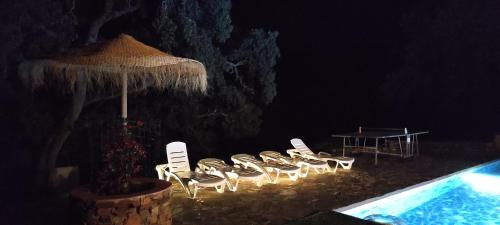 - un groupe de chaises et un parasol à côté de la piscine dans l'établissement Casa Rural Monterrey Aroche, à Aroche
