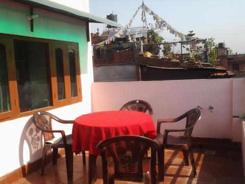 a table with chairs and a red table cloth on a balcony at Ajima Guest House in Bhaktapur