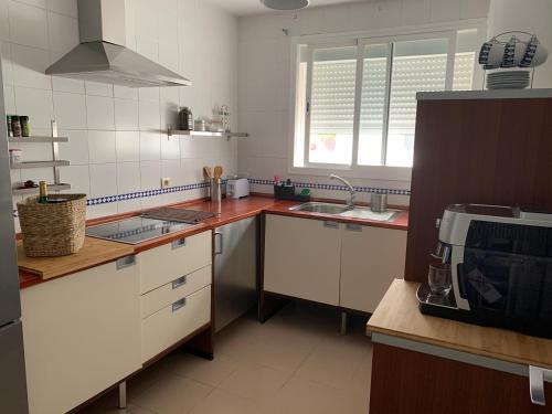 a kitchen with white cabinets and a sink and a microwave at Mirador de la ría, Isla Cristina in Isla Cristina