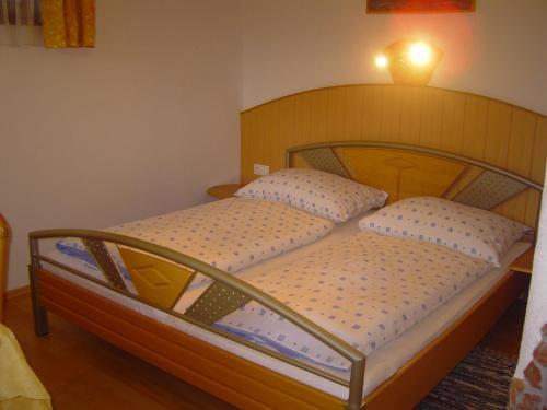 a bed with a wooden headboard and two pillows at Appartement Pichler in Radstadt