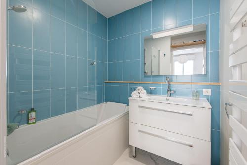 La salle de bains bleue est pourvue d'un lavabo, d'une baignoire et d'une baignoire. dans l'établissement ✵ Le Saint Georges- T2 4P+ Wifi + Parking à Disney - Fairytale Factory ✵, à Bussy-Saint-Georges