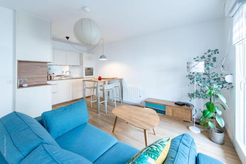 un salon avec un canapé bleu et une cuisine dans l'établissement ✵ Le Saint Georges- T2 4P+ Wifi + Parking à Disney - Fairytale Factory ✵, à Bussy-Saint-Georges