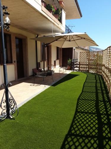 a yard with green grass and an umbrella on a house at Affittacamere La Madonnina in San Giovanni Rotondo