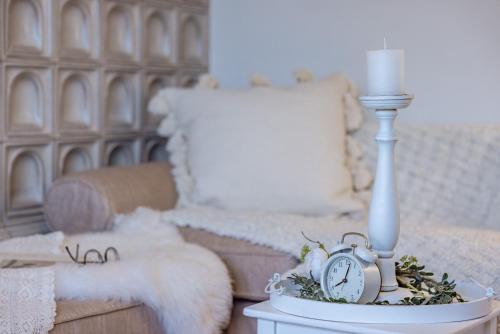 a table with an alarm clock and a candle and a couch at die weisse Wand in Weissensee