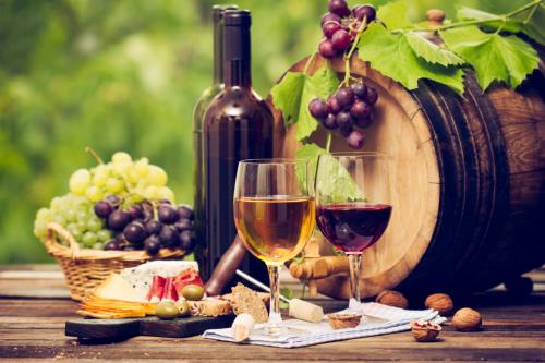 a table with two glasses of wine and grapes at Charming traditional 2-Bed Cottage near Plemet in Plémet