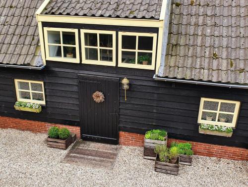 a black house with a black door and potted plants at Op Stolk bed & breakfast in Stolwijk