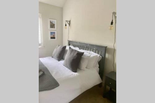 - une chambre avec un lit doté de draps et d'oreillers blancs dans l'établissement Self contained annexe in the heart of Wedmore, à Wedmore