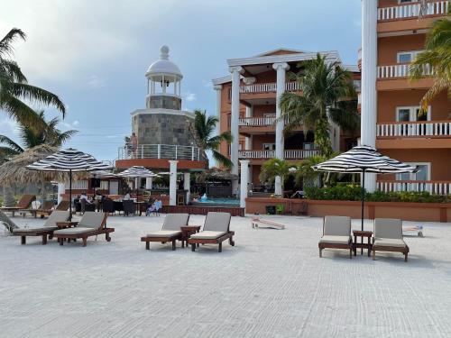 a courtyard with chairs and umbrellas in front of a building at Lighthouse Beach Villas in San Pedro