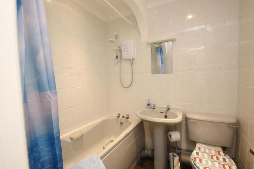 a bathroom with a tub and a sink and a toilet at 43C Medmerry Park 2 Bedroom Chalet in Earnley