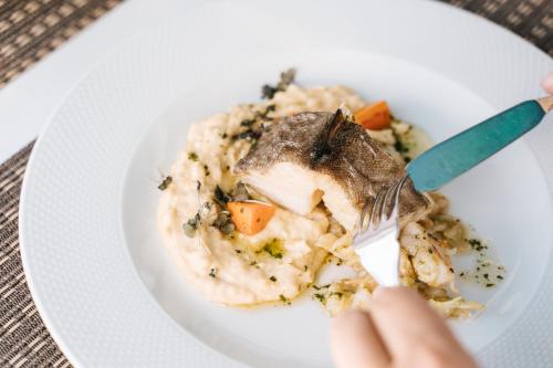 a person eating a plate of food with a fork at Conimbriga Hotel do Paço in Condeixa a Nova