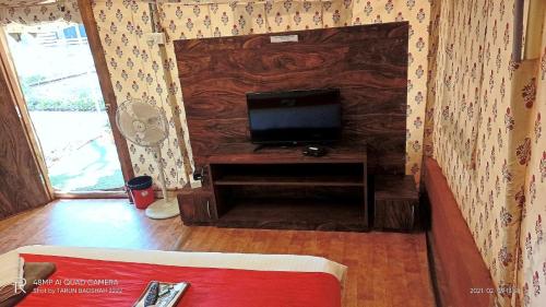 sala de estar con TV de pantalla plana en la pared en Adventure Camping, en Pachmarhī